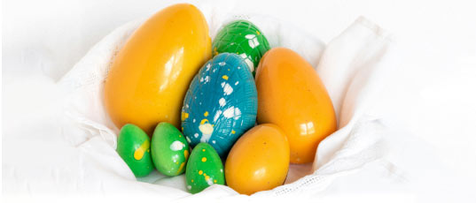 huevos de pascua de chocolate con colores vibrantes, con un acabado brillozo de azul y amarillo sobre un fondo blanco. 